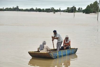 Villagers travel by boat to reach their homes cut off by floodwaters following heavy rains in Kapurthala district of northern state of Punjab, India