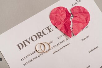 A divorce paper with two engagement rings and a broken paper heart