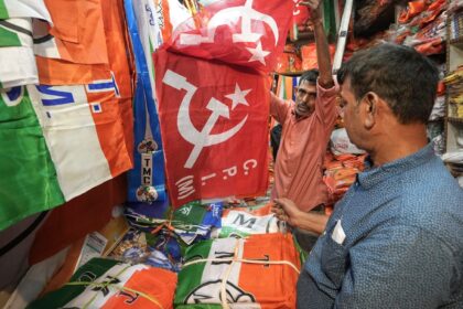 A shopkeeper shows flags with depictions of CPI(M) party logo at his shop, ahead of the West Bengal Assembly elections, in Kolkata, Tuesday, March 24, 2026.