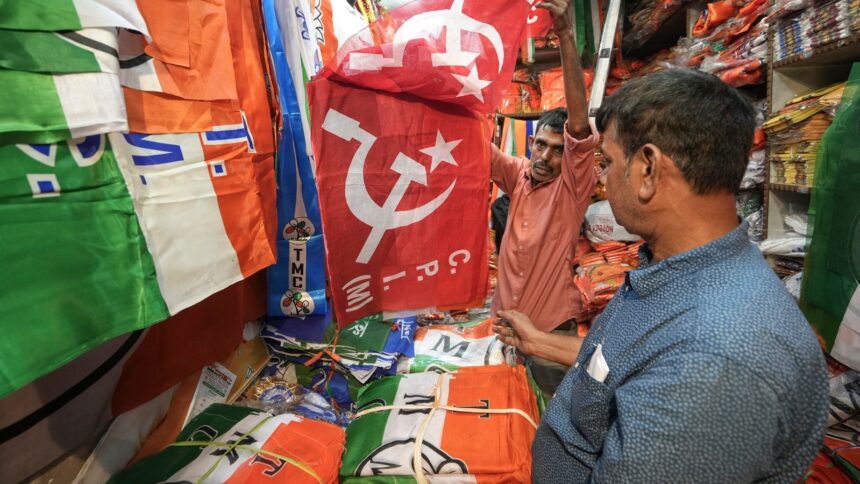 A shopkeeper shows flags with depictions of CPI(M) party logo at his shop, ahead of the West Bengal Assembly elections, in Kolkata, Tuesday, March 24, 2026.
