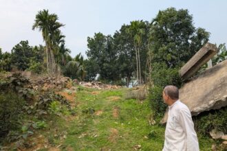 A camp resident, Suleman Ali, near this house in the Hasila Beel wetland area of Assam’s Goalpara district that was demolished during a large-scale eviction drive last June. (Express Photo/Sukrita Baruah)