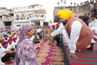 Punjab Chief Minister Bhagwant Mann speaks with a woman at a public gathering as the state prepares to launch the Mawan Dhiyan Satkar Yojana financial aid scheme for eligible women vote beneficiaries.