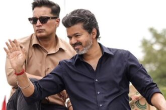 Tamil Nadu Chief Minister Joseph Vijay greets the gathering at a roadshow during his first official visit to Karur after he took up the reins as Chief Minister, in Karur. (@TVKPartyHQ/X via PTI Photo)